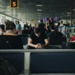 a group of people all looking at their phones in an airport