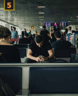 a group of people all looking at their phones in an airport
