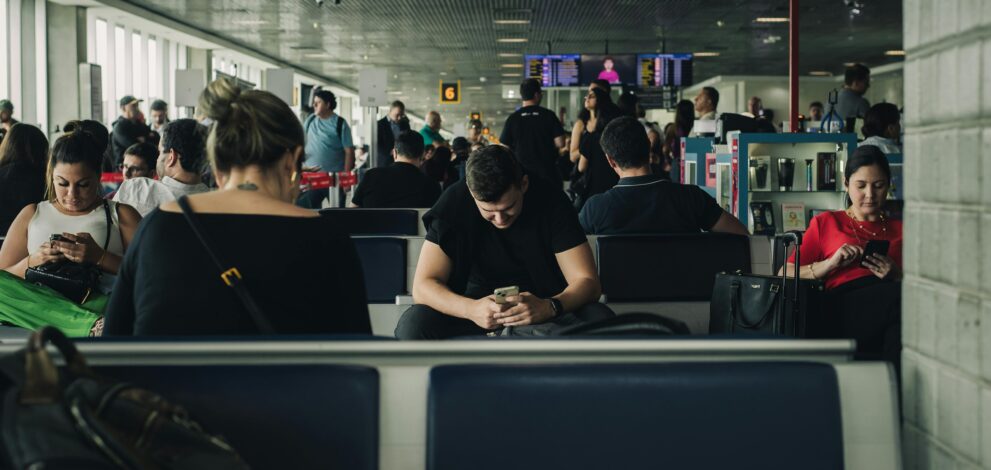 a group of people all looking at their phones in an airport