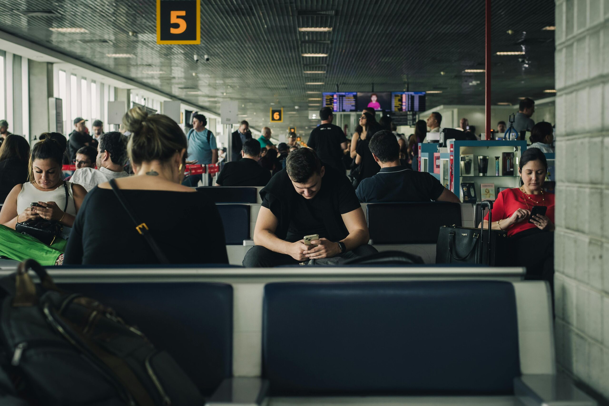 a group of people all looking at their phones in an airport