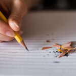 a picture of someone writing with a pencil that is breaking