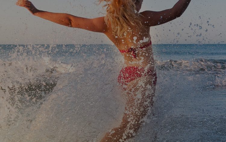 a woman in a bathing suit running into the ocean