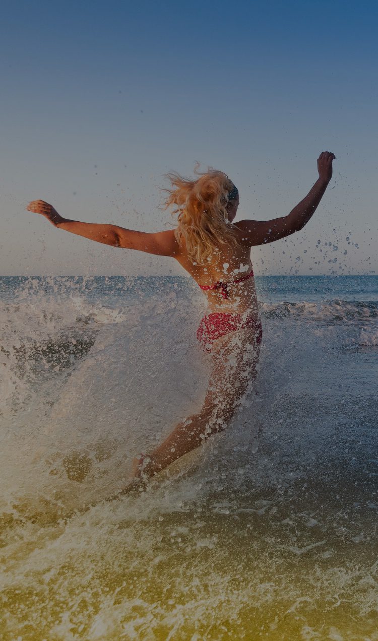 a woman in a bathing suit running into the ocean